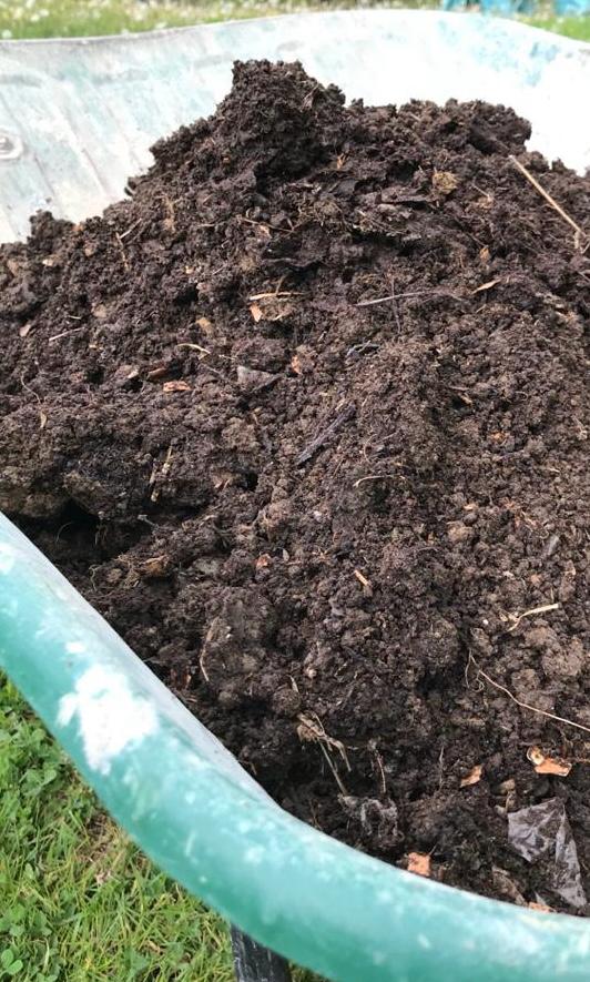 Wheelbarrow filled with fertile loamy garden soil for planting